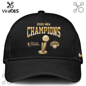 Black baseball cap featuring gold 2026 NBA Champions text, Larry O'Brien trophy graphic, and New York Knicks logo.!