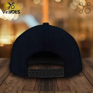 Rear view of a navy blue baseball cap with an adjustable black plastic snapback closure on a wooden surface.!