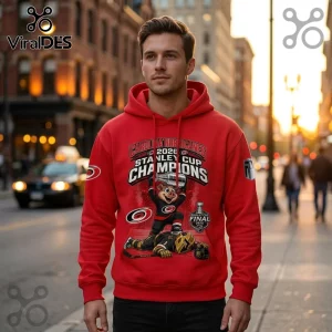 Man wearing red hooded sweatshirt featuring Carolina Hurricanes 2026 Stanley Cup Champions graphic and hockey mascot print.!