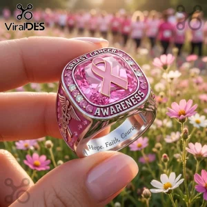 Silver ring with pink breast cancer awareness ribbon, central pink gem, caduceus emblem, and text Hope, Faith, Courage.!
