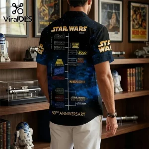 Man wearing short-sleeve button-up shirt featuring a navy blue Star Wars timeline graphic with gold text and logos.!