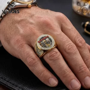 Gold Iron Maiden signet ring featuring Eddie the mascot, red text, and diamond pavé border worn on a human ring finger.!