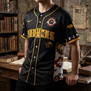 Black baseball jersey with gold piping, dragon scale pattern, yellow Mudhens lettering, and a round embroidered crest.!