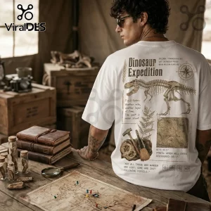 Man wearing a white cotton t-shirt with a vintage Dinosaur Expedition graphic featuring a T-Rex skeleton and field notes.!