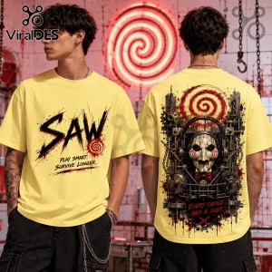 Yellow short-sleeve cotton t-shirt featuring Saw horror movie branding, Billy the Puppet graphic, and spiral motifs.!