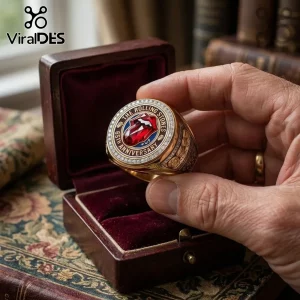 Rolling Stones 65th Anniversary gold ring featuring a central red gemstone tongue logo in a velvet-lined wooden box.!