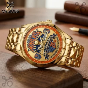 Gold-toned New York Knicks 2026 championship wristwatch with blue, orange, and white dial detailing on a wooden surface.!