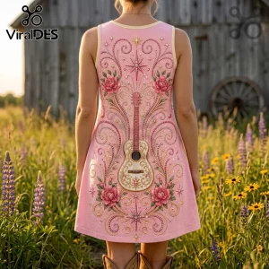 Woman wearing a pink tank dress featuring a guitar graphic surrounded by ornate floral scrolls and star motifs in a field.!