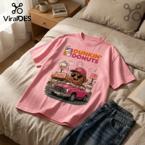 Dunkin Donuts Pink Vintage Mascot T-Shirt featuring a graphic of a donut character in a pink car at a coffee shop.