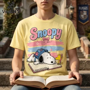 Yellow cotton t-shirt with a Snoopy graphic featuring Snoopy sleeping on a notebook next to Woodstock in pastel colors.!