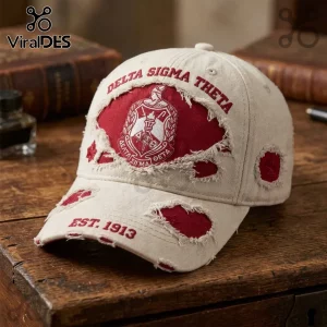 Distressed beige baseball cap featuring red Delta Sigma Theta embroidery, crest emblem, and EST. 1913 text on rustic wood table.!