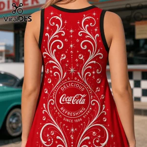 Red Coca-Cola branded tank top with white filigree scrollwork, bubbles, stars, and 1886 text on a blurry diner background.!