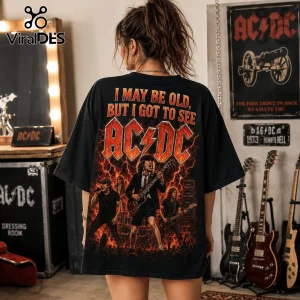 Vintage AC/DC I May Be Old Band T-Shirt on a woman, black oversized cotton tee with fire graphics and Angus Young print.