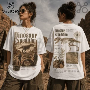 White oversized t-shirt featuring Dinosaur Expedition graphic with T-Rex skeleton, topographical maps, and field notes text.!