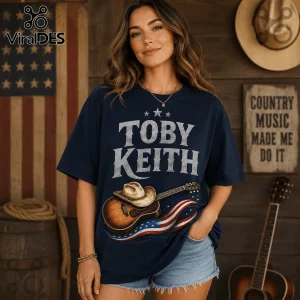 Toby Keith 9/11 25th Anniversary T-Shirt in navy blue featuring a cowboy hat, acoustic guitar, and American flag graphic.