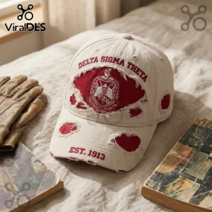 Beige distressed baseball cap with red embroidered Delta Sigma Theta crest and Est. 1913 text on a fabric surface.!