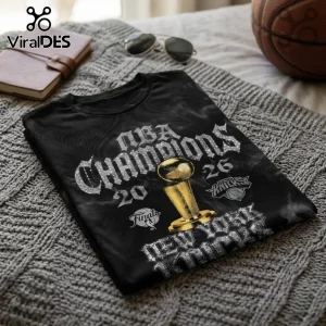 Black cotton t-shirt featuring silver NBA Champions 2026 text, a gold Larry O'Brien trophy, and the New York Knicks logo.!