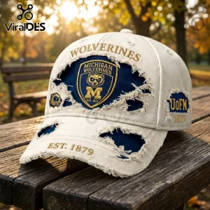 Distressed white baseball cap featuring Michigan Wolverines logo, embroidery, and gold text on a wooden park bench.!