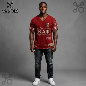 Man wearing a distressed red Kappa Alpha Psi V-neck jersey with Greek letters, 1911 text, and patches over dark jeans.!