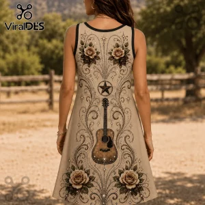 Woman wearing a beige tank dress featuring a western acoustic guitar, star, and floral scrollwork print against a fence.!