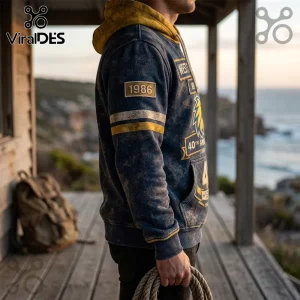 Distressed navy blue hoodie with yellow hood and 1986 patch, featuring vintage coastal anniversary graphics on wood deck.!