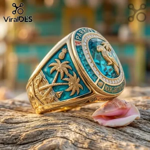 Jimmy Buffett Margaritaville gold parrot ring featuring a blue stone, palm trees, and tropical engraving on wood surface.