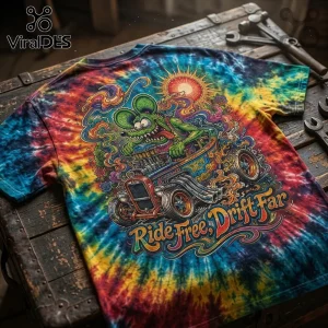Tie-dye t-shirt featuring a green rat character driving a hot rod with Ride Free, Drift Far text on a wooden table.!