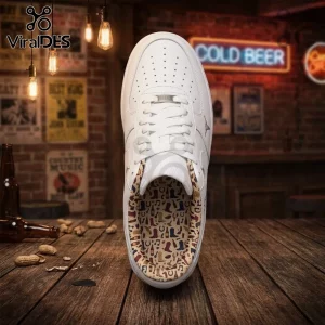 White leather sneaker with a patterned interior showing cowboy boots, horseshoes, and guitars on a wooden bar table.!