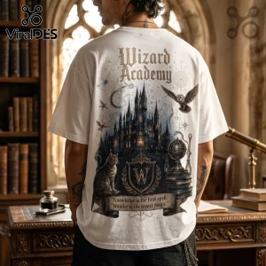 White t-shirt featuring a Wizard Academy graphic, gothic castle, owl, cat, and text reading Knowledge is the first spell.!