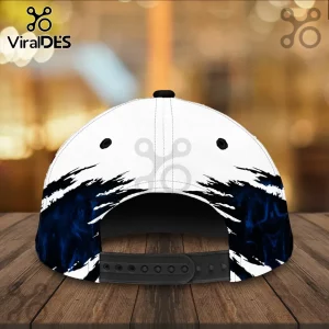 Baseball cap with white base and black and dark blue smoke-effect claw mark graphics on a wooden surface.!