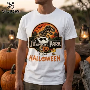 Snoopy x Jurassic Park Halloween white t-shirt featuring Snoopy wearing sunglasses and holding a pumpkin by a T-Rex logo.