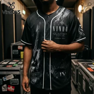 Black baseball jersey with white trim, featuring Ninho Quattro Tour 2027 text, abstract grey splatter, and roman numeral IV.!