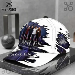 Eagles Band 50th Anniversary Greatest Hits baseball cap featuring a band photo and purple cosmic graphic on white fabric.