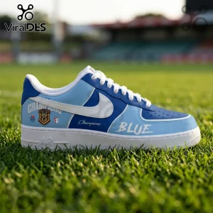 Custom blue and white leather sneaker featuring Champions text and a sports crest on a blurred grass field background.!