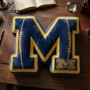 Plush letter M pillow in navy blue and yellow velvet with embroidered football lace details and collegiate M logo patch.!