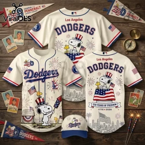 Los Angeles Dodgers baseball jerseys and hat featuring Snoopy, fireworks, and USA flag graphics on cream fabric.!