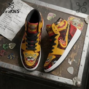 Guns N' Roses high-top sneakers with yellow, black, and red graphics, guitar picks, and a setlist on a wooden surface.!