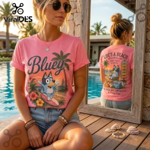 Pink cotton t-shirt featuring Bluey surfing, palm trees, hibiscus flowers, and Life's A Beach text graphic on the back.!