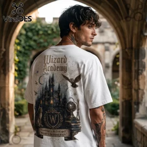 Man wearing a white t-shirt featuring Wizard Academy text, a castle graphic, an owl, and books in a stone archway background.!