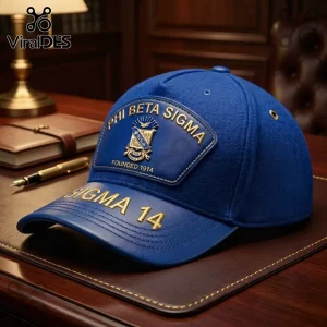 Blue wool and leather baseball cap featuring Phi Beta Sigma fraternity logo and gold embroidery on a dark wood desk.!