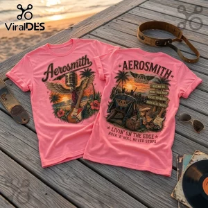 Pink Aerosmith graphic t-shirts with retro microphone, guitar, and beach scene prints on a wooden deck background.!