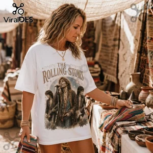 Woman wearing a white Rolling Stones graphic t-shirt with vintage-style band artwork in an outdoor market setting.!