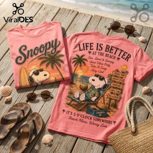 Pink cotton t-shirts with Snoopy beach graphics, surfboards, palm trees, and tropical text on a wooden deck with seashells.!