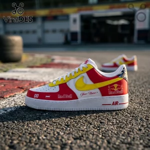 Custom Red Bull Racing Nike Air Force 1 sneakers in white, red, and yellow with branded logos on a race track background.