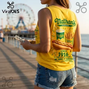 Nathan's Famous Since 1916 V-Neck Tank Top in yellow worn by a person holding food on a pier with a ferris wheel background.