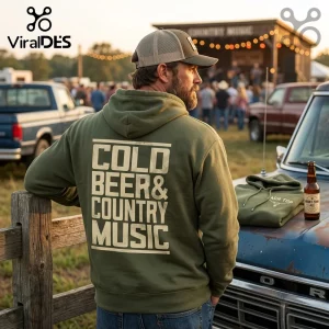 Man wearing an olive green hoodie with Cold Beer & Country Music printed in white on the back at an outdoor concert.!