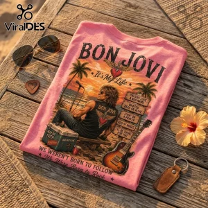 Pink Bon Jovi t-shirt featuring beach graphic, song titles, guitar, and sunset on a wooden table with sunglasses and flower.!