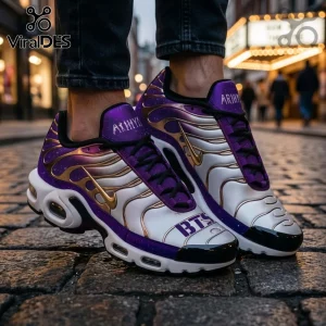 BTS ARMY Purple Galaxy Air Max Plus sneakers featuring white, purple, and gold accents on a cobblestone city street.