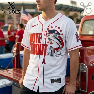 White Mike Trout baseball jersey featuring red text Vote Trout, a fish graphic, and Angels logo in a stadium parking lot.!