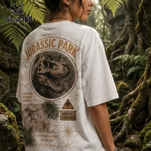White oversized t-shirt featuring a vintage Jurassic Park dinosaur skull graphic with text about survival and danger.!